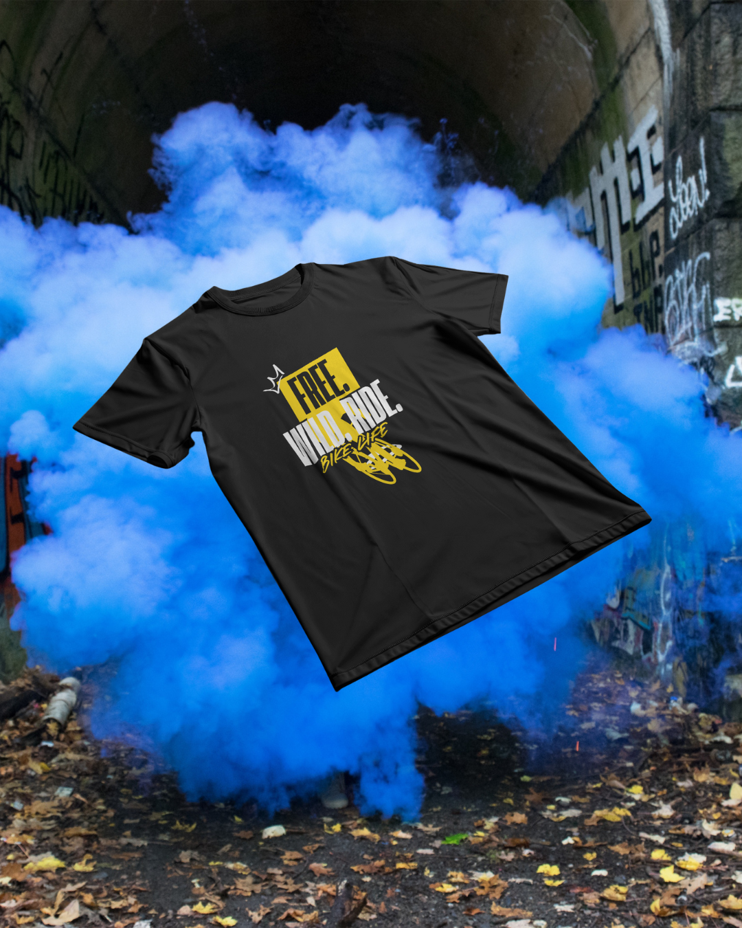 Cycle Swagger 'Royal Ride' T-shirt with 'FREE. WILD. RIDE. BIKE LIFE' graphic, featured in a dynamic shot with blue smoke against an urban graffiti tunnel background.