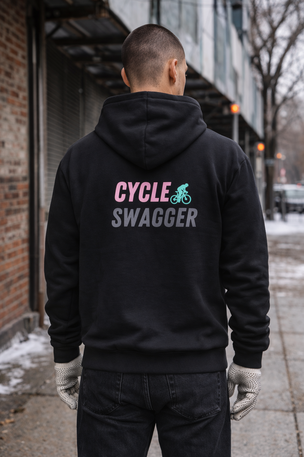 Person wearing a black hoodie with 'Cycle Swagger' text on the back, standing on a sidewalk.
